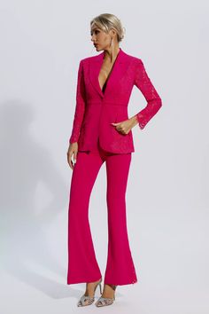 a woman in a bright pink suit and matching heels stands with her hands on her hips