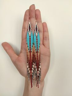 a hand holding a pair of beaded earrings