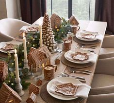 a table set for christmas with gingerbread house decorations