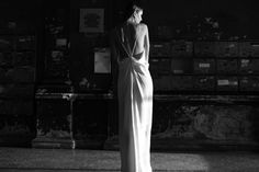 a woman in a long white dress standing next to a wall with mail boxes on it