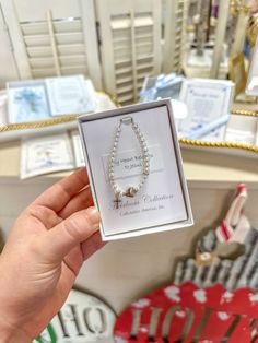 a person holding up a pearl necklace in a store display case with other jewelry on it