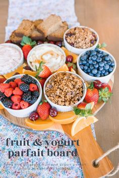 fruit and yogurt parfait board on a wooden tray with berries, oranges, strawberries, bread