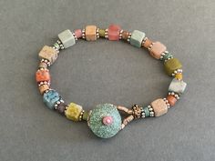 This is an especially pretty pastel agate beaded bracelet. It is made with agates that are pastel colors including blue, green, pink, beige,and coral. There are small rondel beads in between the square beads. The  pastel bracelet has silver spaces and a turquoise button and beaded loop closure. You will choose to wear this special pastel bracelet often because the  soft colors are so appealing and is the perfect accessory for many occasions.  7 1/2" long Handmade Bohemian Beaded Bracelets In Pastel, Handmade Bohemian Pastel Beaded Bracelets, Handmade Pastel Bohemian Bracelets, Multicolor Crystal Bracelet With Spacer Beads For Healing, Multicolor Stretch Bracelet With Round Natural Stones, Multicolor Stretch Bracelet With Natural Stones In Round Beads, Pastel Beaded Bracelets With Colorful Round Beads, Multicolor Natural Stones Beaded Bracelets For Jewelry Making, Multicolor Gemstone Bead Bracelets