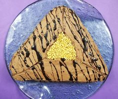 a piece of cake with chocolate icing and sprinkles in the shape of a triangle