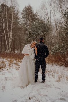 a bride and groom standing in the snow