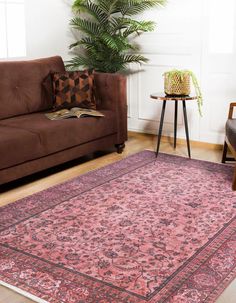 a living room with a couch, chair and rug on the floor in front of a potted plant