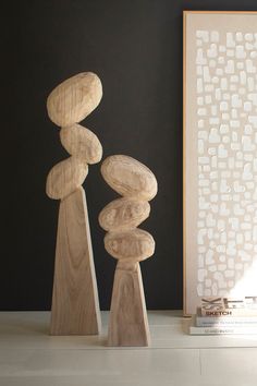 three wooden sculptures sitting on top of a white table next to a framed photo and book