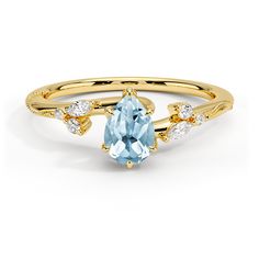 a yellow gold ring with an aqua blue topazte and white diamonds on it