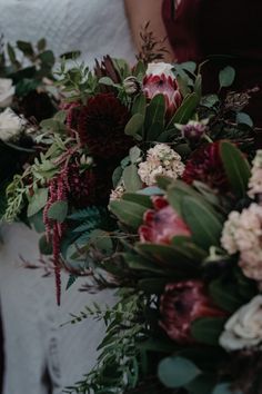 the bride and groom are holding their wedding bouquets with red, white and green flowers