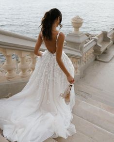 a woman in a white dress is walking down some stairs by the water with her hand on her hip