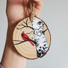 a hand holding a piece of wood with a red bird on it