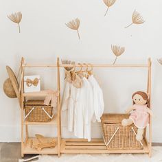 a baby's room with clothes and toys on the rack, including a doll