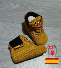 a pair of yellow crocheted shoes sitting on top of a wooden floor next to a