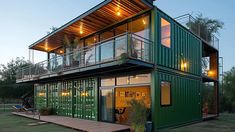 a large green container home sitting on top of a lush green field