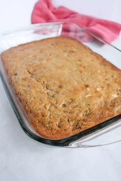 a glass baking dish filled with baked goods on top of a white tablecloth and pink napkin