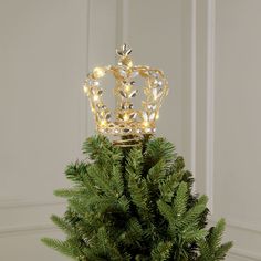 a small christmas tree with a gold crown on it's top and lights in the middle