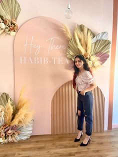 a woman standing in front of a sign that says hey there habi - tea