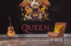 a room with a guitar, chair and wall mural that says queen written on it