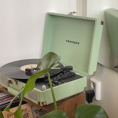 a record player sitting on top of a wooden table next to a potted plant