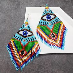 a pair of colorful beaded earrings sitting on top of a white tray next to each other