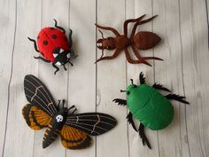 four bugs, two ladybugs and one spider on white wood