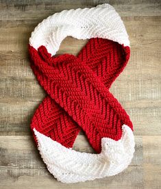 a red and white knitted scarf sitting on top of a wooden floor