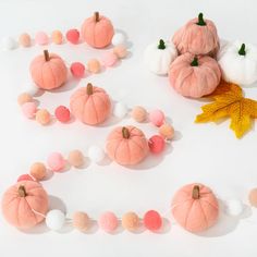 several small pumpkins and cotton balls are arranged on a white surface with autumn leaves