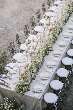 a long table with white plates and flowers on it is set up for an event