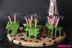 green frosted cake with candy sticks sticking out of it on a wooden platter