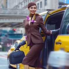 a woman standing next to a taxi with her hand on the door and holding luggage