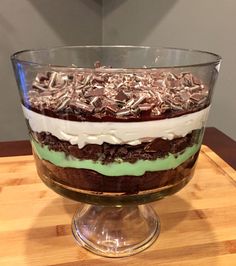 a dessert dish with chocolate, cream and green frosting on a wooden table in front of a gray wall