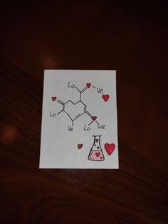 a piece of paper with hearts and chemical symbols drawn on it sitting on a table