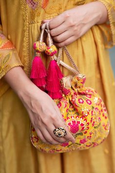 "Our Alanna potli is detailed with thread and zari and sequin embroidery on soft silk. Pair this with a vibrant pink ensemble and watch it stand out as a statement accessory! Colour: Mustard with pink Embroidered front and back. Dimensions (LxB): 8.5\"×9.5\" Handle drop: 5\" Material : Embroidered silk, gold tissue, poly satin lining, woven gold thread drawstrings and silk thread tassle detailing." Festive Pink Potli Bag For Party, Multicolor Embroidery Handwork Potli Bag, Festive Pink Embroidered Shoulder Bag, Festive Pink Handcrafted Shoulder Bag, Pink Zari Work Potli Bag For Party, Bollywood Gota Work Embroidered Fabric For Party, Bollywood-style Gota Work Embroidered Fabric For Party, Festival Multicolor Embroidery Potli Bag With Zari Work, Festive Multicolor Embroidery Potli Bag With Zari Work