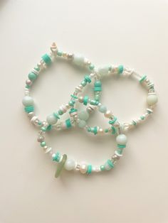 "the \"sea treasures\" bracelets are made by tons of different charms and beads. they're a very unique set of bracelets that are perfect for any summer look don't wear this in the water, the knot will come undone. please don't stretch it, it will break. not recommended for children under 8 as small objects could present as a choking hazard." Bohemian Beaded Charm Bracelet For Beach, Ocean-inspired Turquoise Beaded Bracelets, Green Bracelets For Beach Season Gift, Green Hand Wrapped Beaded Bracelets For Beach, Handmade Green Beaded Strand Bracelets, Adjustable Ocean-inspired Beaded Bracelets With Lobster Clasp, Beaded Charm Bracelet For Beach With Round Beads, Adjustable Charm Bracelet With Round Beads For Beach, Ocean-inspired Beaded Bracelets With Round Beads