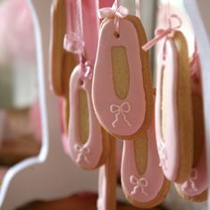 some cookies are hanging from a rack with pink ribbon and bows on it's handles