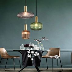 a dining room table with four chairs and three pendant lights hanging from it's ceiling