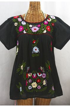 The "La Mariposa Libre" Mexican Blouse by Siren: * Ornate hand embroidery with open sleeves, available here in BLACK with MULTI-COLORED embroidery. * Dyed, distressed and embroidered entirely by hand for an authentic, retro-vintage and hippie casual vibe. * Light, gauzy and semi-sheer 100% cotton throughout; wear it billowy and flowing in the traditional bohemian style. * Our ornate butterly floral embroidery patterns are a faithful tribute to the original Mexican style hippie blouses of the 197 Traditional Short Sleeve Blouse With Tonal Embroidery, Traditional Short Sleeve Embroidered Top With Tonal Embroidery, Hippie Blouse, Mexican Blouse, Open Sleeves, Floral Embroidery Patterns, Open Sleeve, Style Blouse, Mexican Style