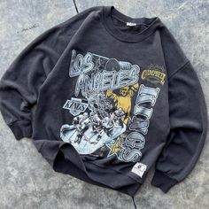 a black sweatshirt with an image of the band's members on it, sitting on concrete