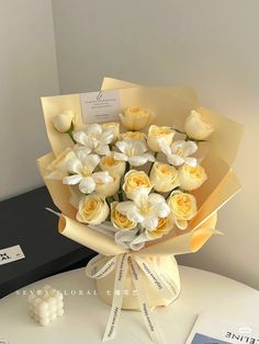 a bouquet of white and yellow flowers sitting on top of a table next to a black box