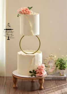 three tiered wedding cake with pink flowers on the top and gold ring around it