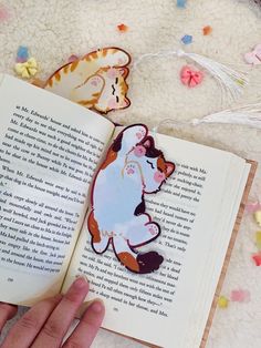 a person is holding an open book with cutouts of cats on it and flowers