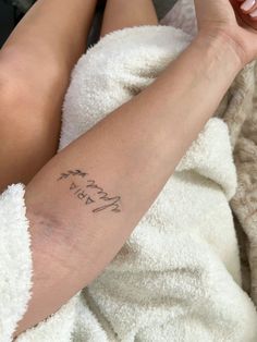 a woman with a tattoo on her arm laying in a bathrobe holding a cell phone