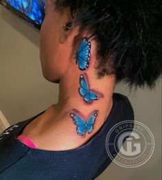 a woman's neck with three blue butterflies tattooed on her upper and lower back