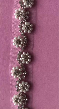 a white beaded bracelet on a pink background