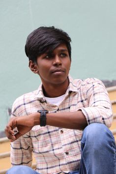 a young man sitting on the steps with his hand resting on his wrist and looking at the camera