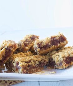 a white plate topped with cookies and bars on top of a wooden table next to a cup