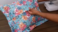 someone is using a sewing machine to sew a flowered pillow on the floor