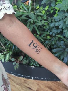 a woman's arm with a tattoo that reads 1950 on the left side of her arm