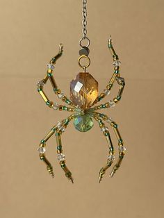 a close up of a spider hanging from a chain with beads and crystals on it