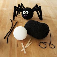 a black spider sitting on top of a wooden floor next to knitting needles and balls